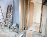 A doorway opening cut back to masonry with a new timber frame fitted, beside metal stud framing on a renovation in progress